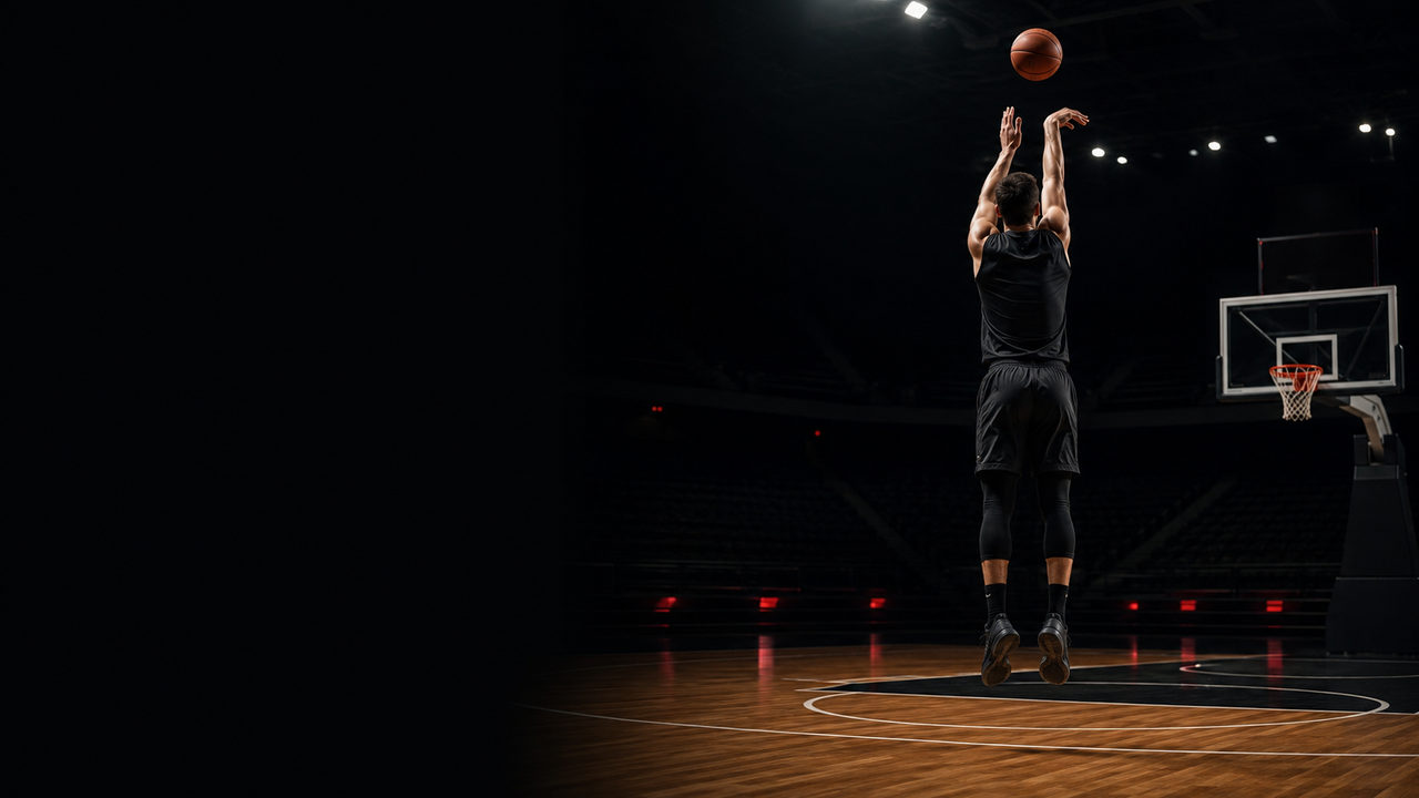 Competitive basketball shooter taking a jump shot in a dark arena